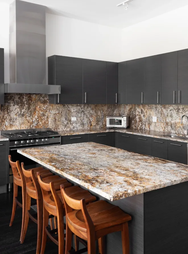 A kitchen with granite counter tops and black cabinets.