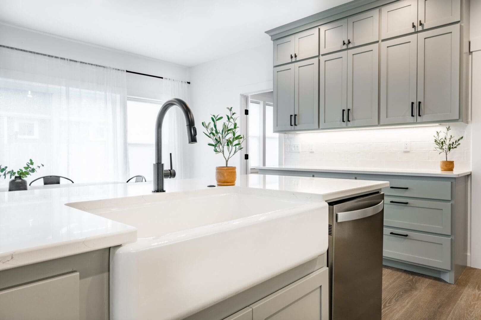 A kitchen with grey cabinets and white counters.