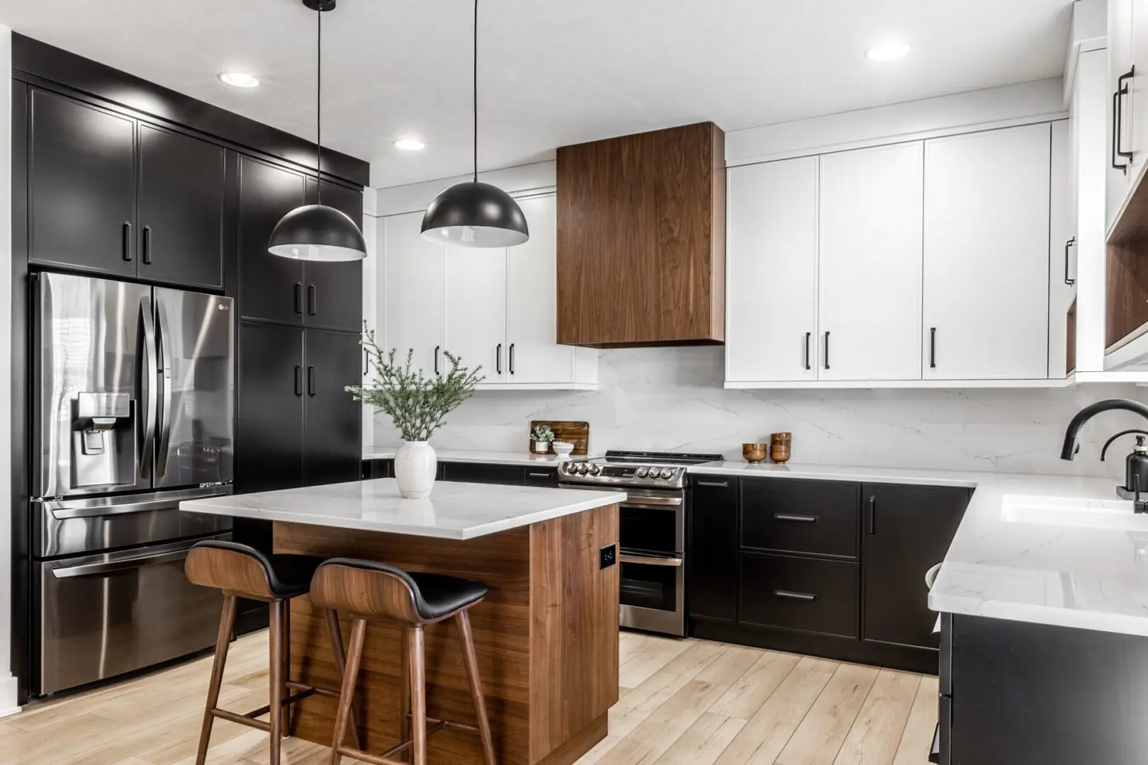 A kitchen with black and white cabinets, wooden island and wood floors.