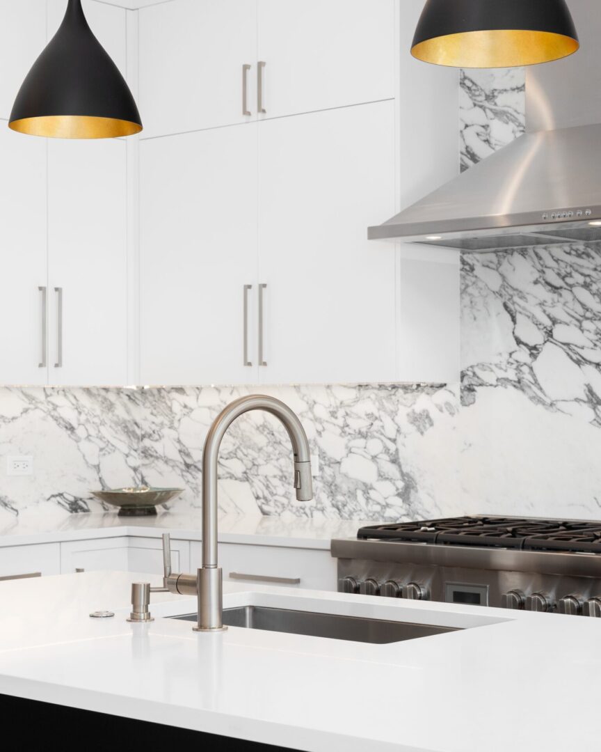 A kitchen with white cabinets and marble countertops.